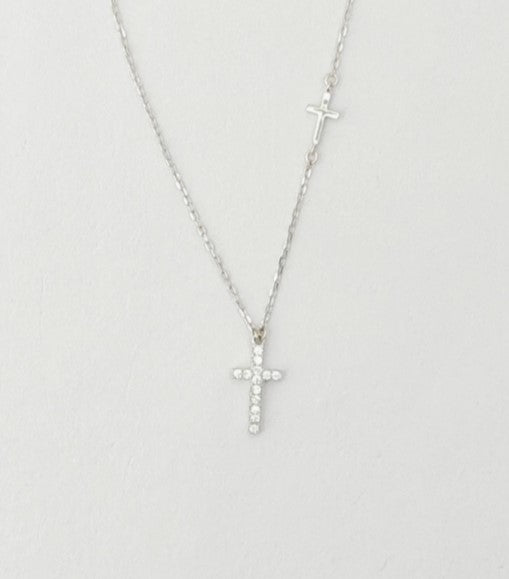 Silver cross necklace on a light gray background